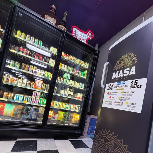 A MASA Empanadas freezer with various beverages and a menu of empanada flavors.