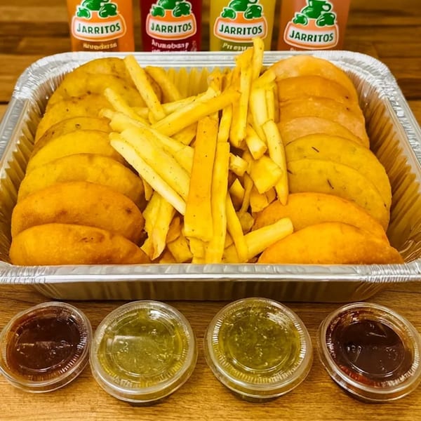 A foil tray of MASA Empanadas and fries, with four Jarritos sodas and dipping sauces.